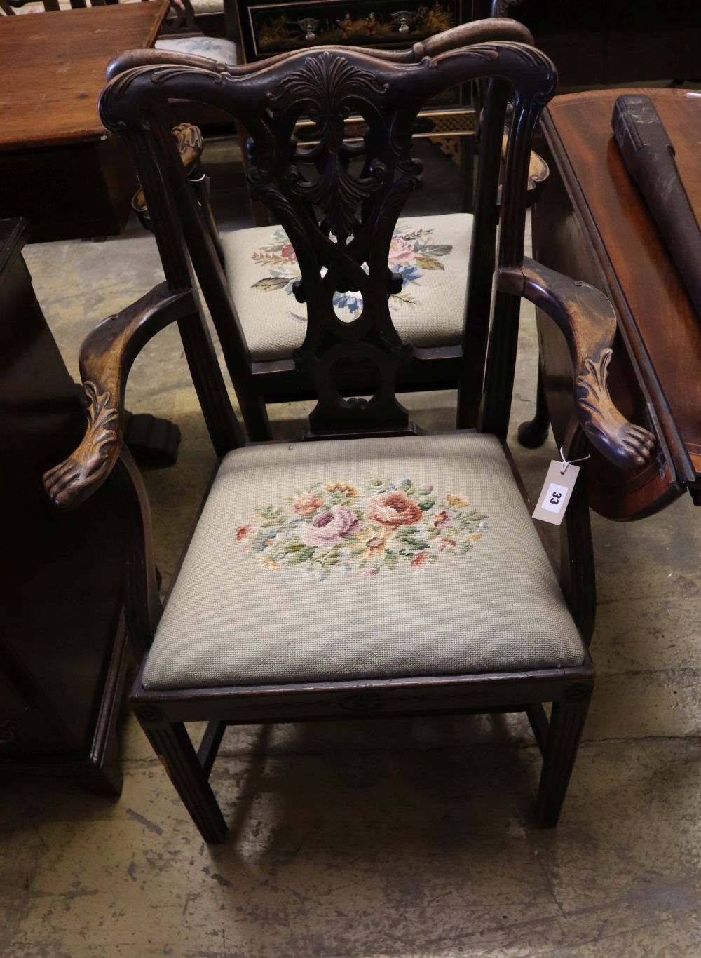 A pair of 19th century mahogany elbow chairs, scroll and leaf-carved and with lions paw armrests